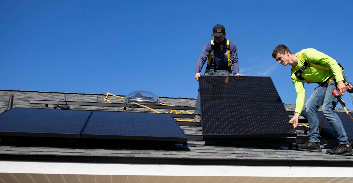 Zwei Monteure setzen Solarmodule auf ein Dach