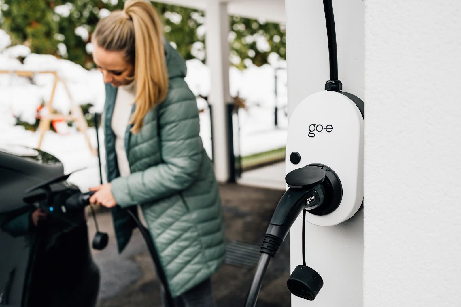 Eine Frau steckt ein Elektroauto an einer Wallbox an